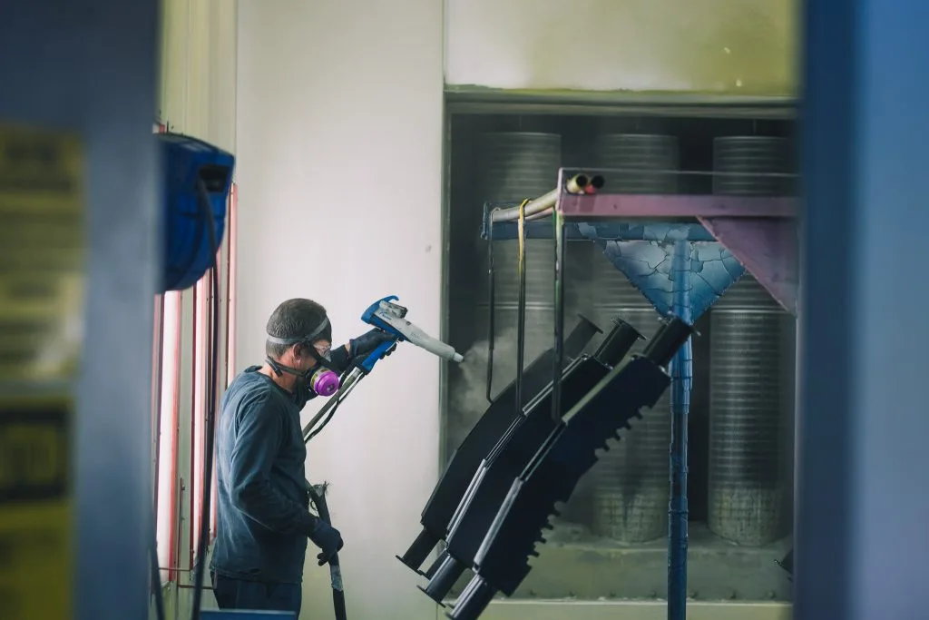 LSM technician powder coating metal parts in the spray booth